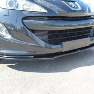 Front-left corner of a dark gray car with a lowered front lip, showing headlight and grille on a sunny road.