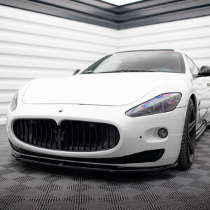Front three-quarter view of a white Maserati sports car in a modern showroom, highlighting the large black grille and trident emblem