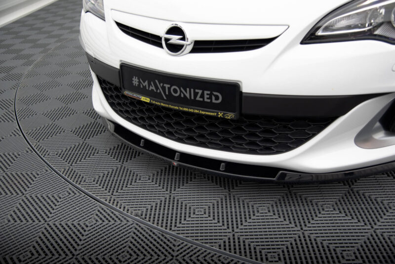 Front view of a white Opel car showing the emblem and a license plate reading #MAXTONIZED on a dark frame.