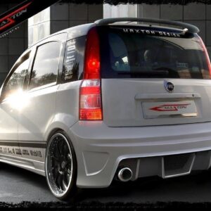 White Fiat hatchback with Maxton Design body kit, large black alloy wheels, and rear spoiler in an urban showroom setting