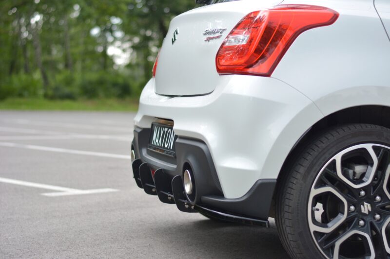 Rear view of a white Suzuki Swift Sport, showing the prominent red tail light and rear bumper in a parking lot.
