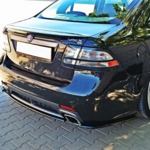 Rear view of a black sedan with Turbo X badge, large silver alloy wheels, and dual exhausts on a brick-paved surface.