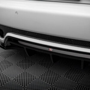 Close-up of a white car's rear bumper showing a carbon-fiber diffuser, small circular parking sensors, and a Harton Design badge.
