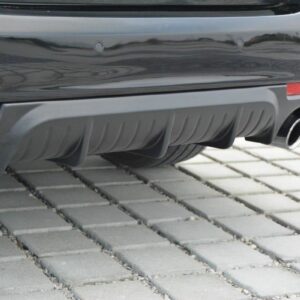 Rear of a dark gray car with dual chrome exhaust tips and a sculpted diffuser on a brick-paved surface.
