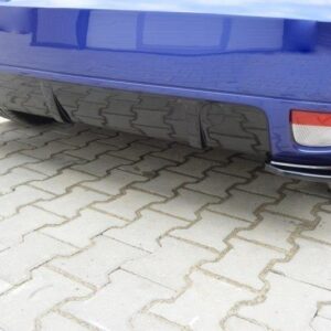 Rear end of a blue car showing the low bumper, left exhaust tip, right tail light, parked on interlocking brick pavement.