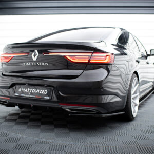 Rear view of a glossy black Renault Talisman in a bright showroom, with distinctive red taillights and the Renault diamond badge visible on the trunk.