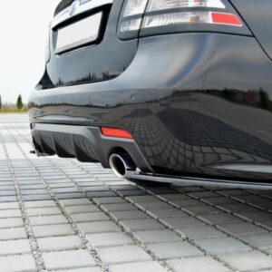 Rear view of a glossy black sedan showing a single exhaust outlet and diffuser on a paved surface.
