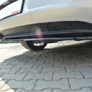 Low-angle view under a white car parked on a brick driveway; exhaust pipe visible on the left and the undercarriage along a paved surface.