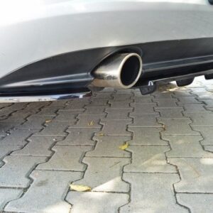 Rear view of a silver car showing a chrome exhaust tip beneath the bumper on a paved driveway edge look.