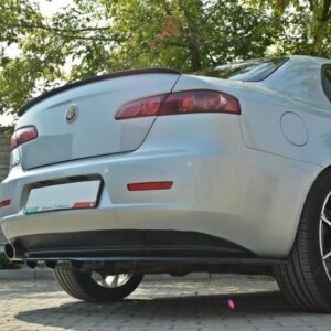 Rear three-quarter view of a silver Alfa Romeo sedan parked on a paved driveway with trees in the background.