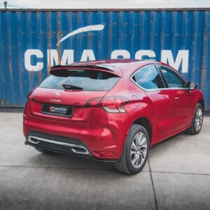 Rear three-quarter view of a red Citroën hatchback parked on a concrete lot in front of a blue shipping container with bold white CMA CGM lettering