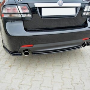 Rear view of a black sedan on a brick-paved driveway, showing two chrome exhaust pipes and a blurred license plate area.