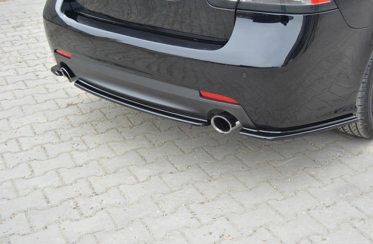 pol_po_Rear-Splitter-suitable-for-Saab-9-3-Aero-Mk2-Facelift-1054_2jpg - OPSHOLDERS Rear view of a black car showing a single chrome exhaust tip, red reflectors, and bumper trim on a paved surface.