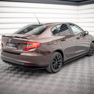 Rear-three-quarter view of a brown Fiat sedan in a bright, industrial showroom with striped walls, front wheels visible.