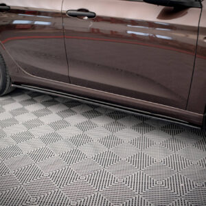 Side view of a brown car showing its doors and part of the wheel, parked on a patterned showroom floor.