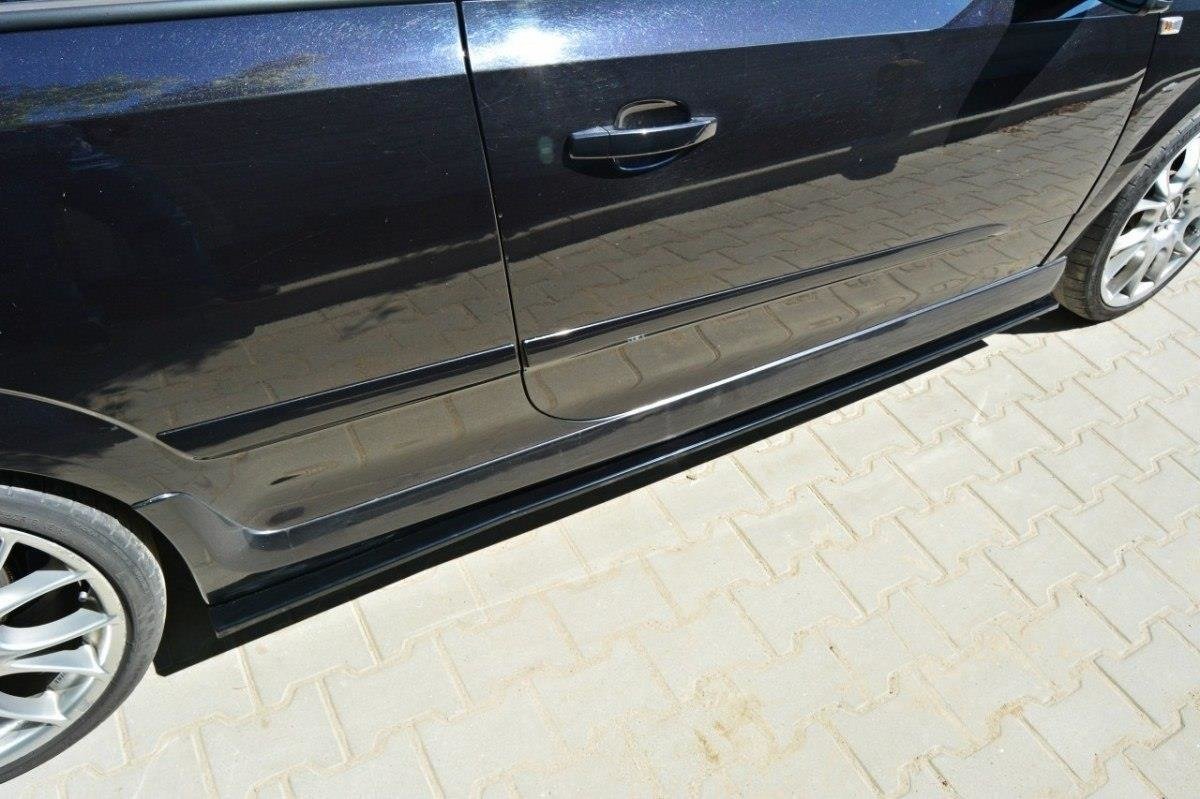 pol_po_SIDE-SKIRTS-DIFFUSERS-suitable-for-Opel-ASTRA-H-FOR-OPC-VXR-238_2jpg - OPSHOLDERS Black car with a lower side skirt and alloy wheels parked on a light-paved surface, reflecting the surroundings on its door panel.