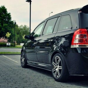 Black Vauxhall Zafira minivan parked in a paved lot, rear three-quarter view with alloy wheels and green trees in the background