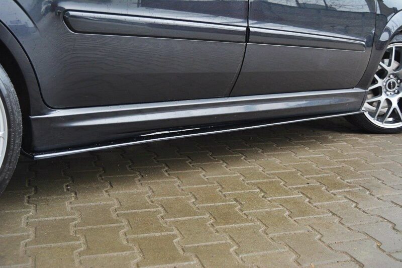pol_po_SIDE-SKIRTS-DIFFUSERS-suitable-for-Opel-ZAFIRA-B-OPC-254_3jpg - OPSHOLDERS Close-up side view of a dark car showing the lower side skirt, door, and alloy wheels on a brick-paved surface, with light scuffs near the bottom edge.