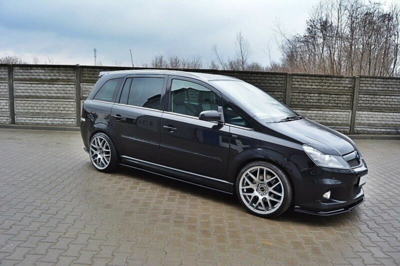 pol_po_SIDE-SKIRTS-DIFFUSERS-suitable-for-Opel-ZAFIRA-B-OPC-254_4jpg - OPSHOLDERS Black minivan with large silver aftermarket alloy wheels parked on a brick driveway in front of a wooden fence.