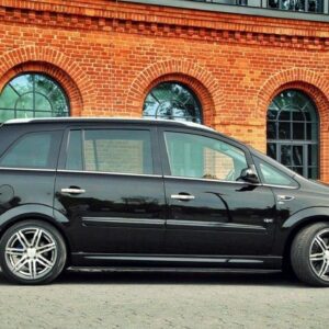 pol_po_SIDE-SKIRTS-DIFFUSERS-suitable-for-Opel-ZAFIRA-B-OPC-254_5jpg - OPSHOLDERS Black MPV parked on a paved lot in front of a red brick building with arched windows.