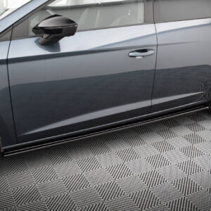 Close-up of a gray sedan's side door and alloy wheel with a reflective paint finish on a patterned floor, showing chrome door handles and a Continental tire.