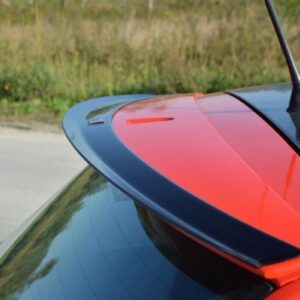 Close-up of a red sports car's rear spoiler with a black edge, outdoors on a sunny day