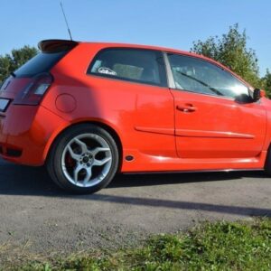 pol_po_SPOILER-CAP-suitable-for-Fiat-STILO-SCHUMACHER-VERSION-1271_4jpg - OPSHOLDERS Red hatchback car parked on a paved road, viewed from the side with a forested background.