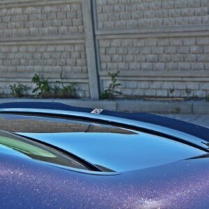 Blue car with a rear spoiler parked in front of a brick wall; close-up of the spoiler and glossy paint.
