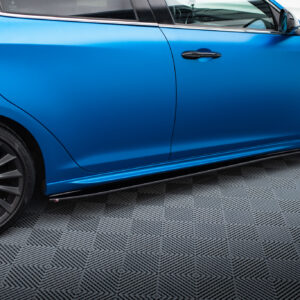 pol_po_Side-Skirts-Diffusers-V-1-suitable-for-Alfa-Romeo-Giulietta-601_4jpg - OPSHOLDERS Close-up of a blue car's side showing the front wheel, alloy rim, brake caliper, door, and side skirt on a checkered floor.