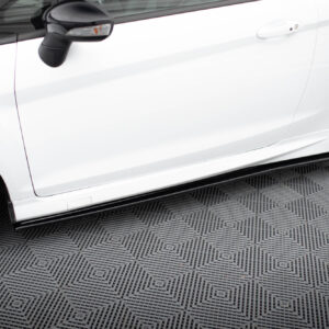 White car side view showing door, side mirror, and black alloy wheel on a patterned floor.