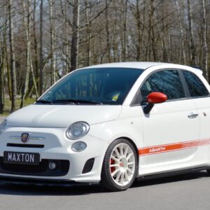 White Abarth hatchback with orange racing stripe, parked in a lot; license plate reads MAXTON, forest background.
