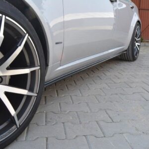 Close-up of a silver car's large black-and-silver multi-spoke alloy wheel with a Tomason center cap, parked on gray brick pavers.
