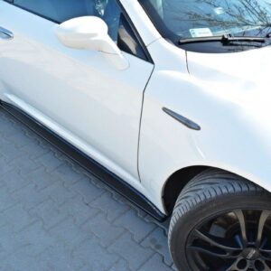 White sports car from a low side angle showing black alloy wheels and red brake calipers, parked on a paved surface.