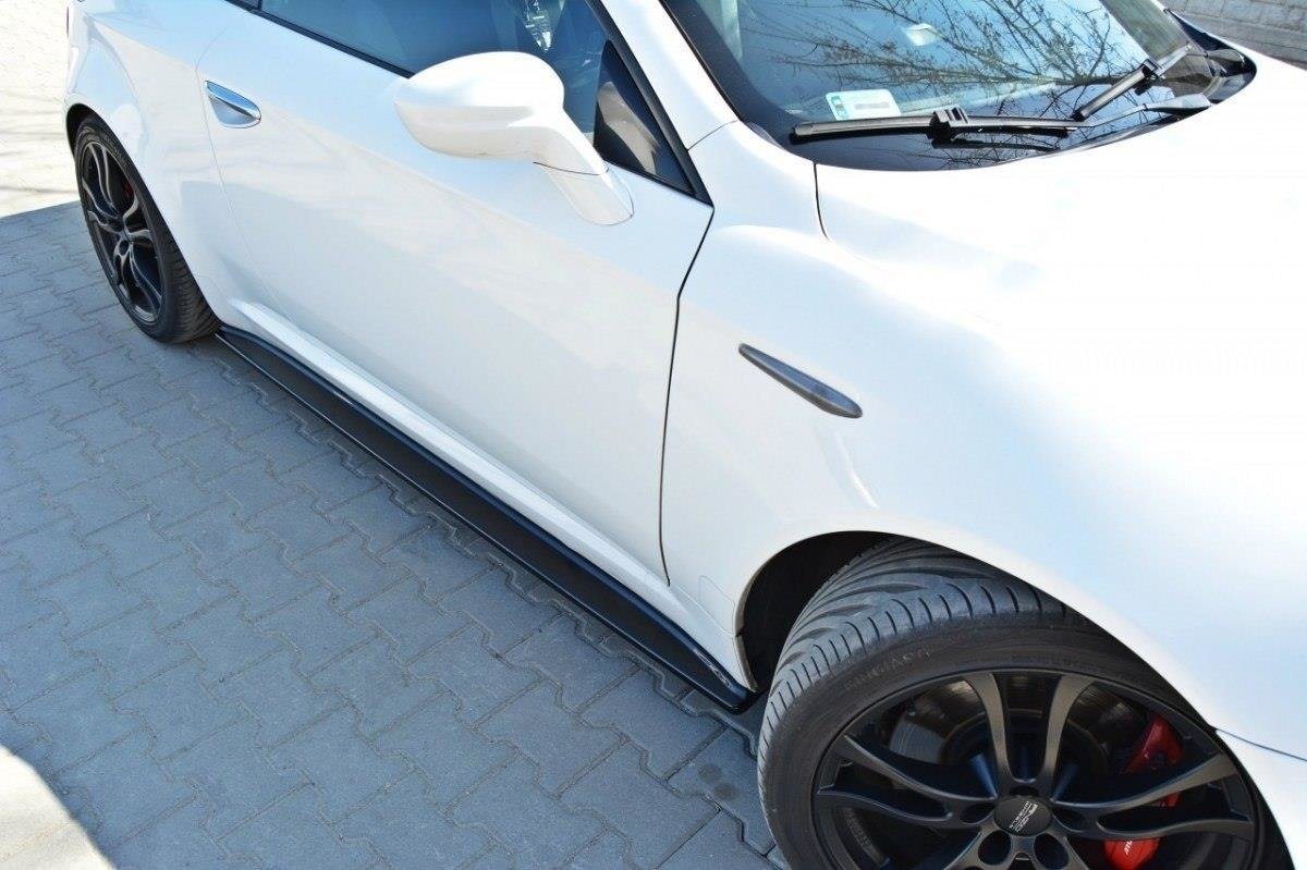 pol_po_Side-Skirts-Diffusers-suitable-for-Alfa-Romeo-Brera-78_2jpg - OPSHOLDERS White sports car from a low side angle showing black alloy wheels and red brake calipers, parked on a paved surface.