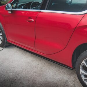 Red car side view with a focus on the front passenger door and chrome trim, parked on a driveway.