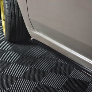 Close-up of a car's front wheel with a bright yellow rim, on a textured dark checkered floor.
