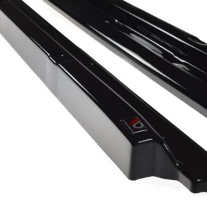 Close-up of glossy black rails or bars with a curved edge, placed diagonally on a white background; a small red-and-white label is visible on one piece.