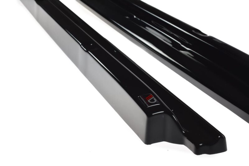 Close-up of glossy black rails or bars with a curved edge, placed diagonally on a white background; a small red-and-white label is visible on one piece.