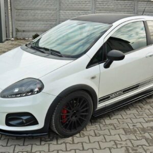 White compact hatchback with black wheels and side stripes labeled Abarth, parked on a brick driveway under a gray fence.