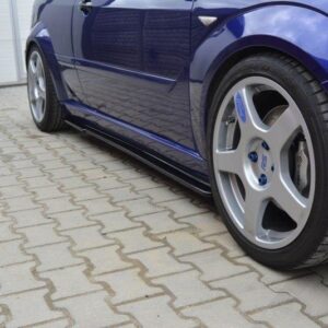 Close-up of a blue sports car's front wheel and side panel with alloy rims on a brick driveway.