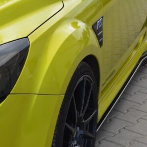 Close-up of a bright yellow sports car showing the front fender, wheel, and side skirt on a paved surface.