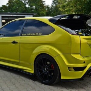 Bright yellow modified hatchback with a large rear wing, black multi‑spoke wheels, and decals on the rear window.