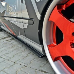 Close-up of a dark gray car side with red aftermarket wheel, visible brake caliper, and PRG decals along the door.",