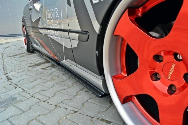 Close-up of a dark gray car side with red aftermarket wheel, visible brake caliper, and PRG decals along the door.",