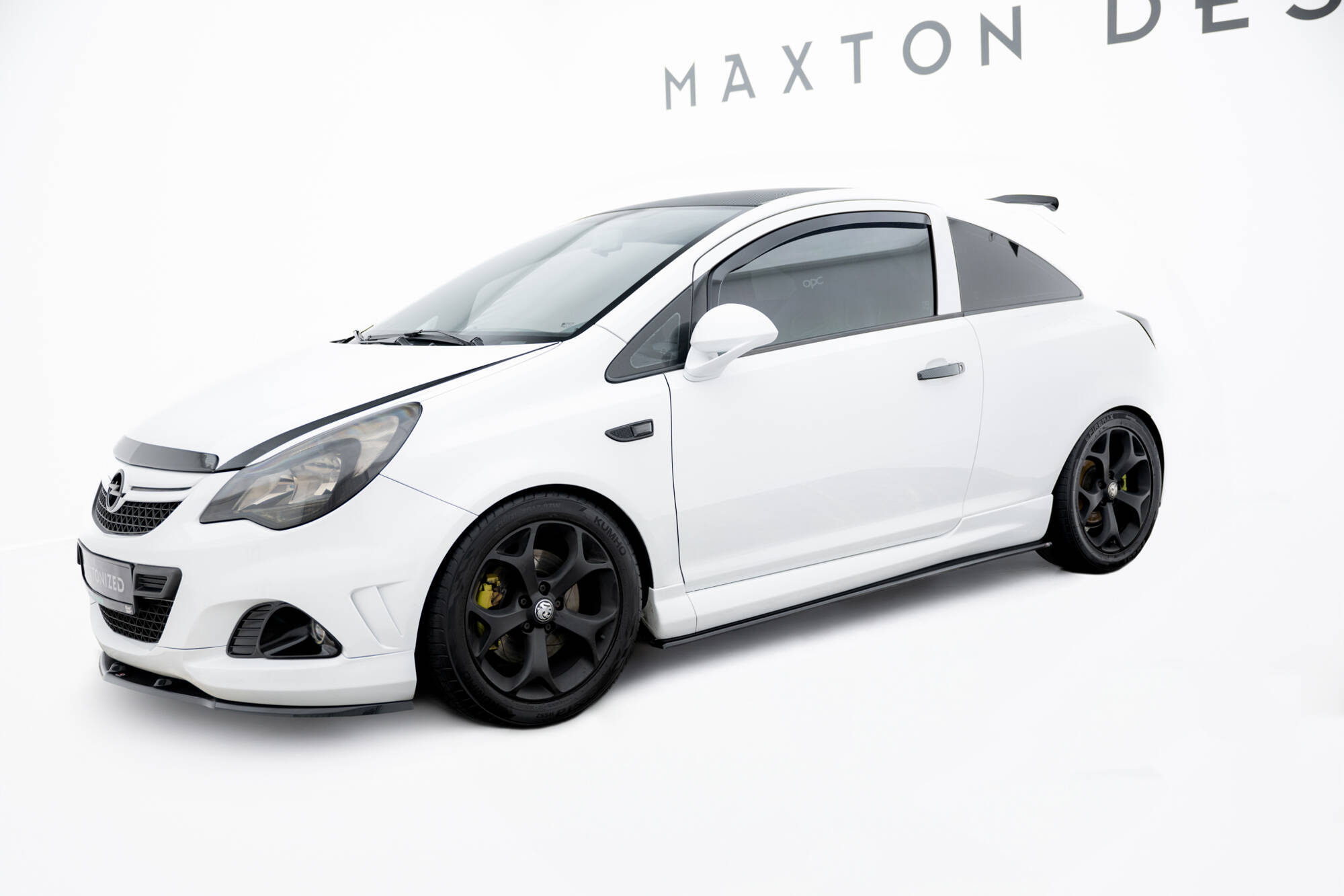 pol_po_Side-Skirts-Diffusers-suitable-for-Opel-Corsa-OPC-VXR-D-245_2jpg - OPSHOLDERS White modified sports car in a studio with Maxton Design banner in the background.