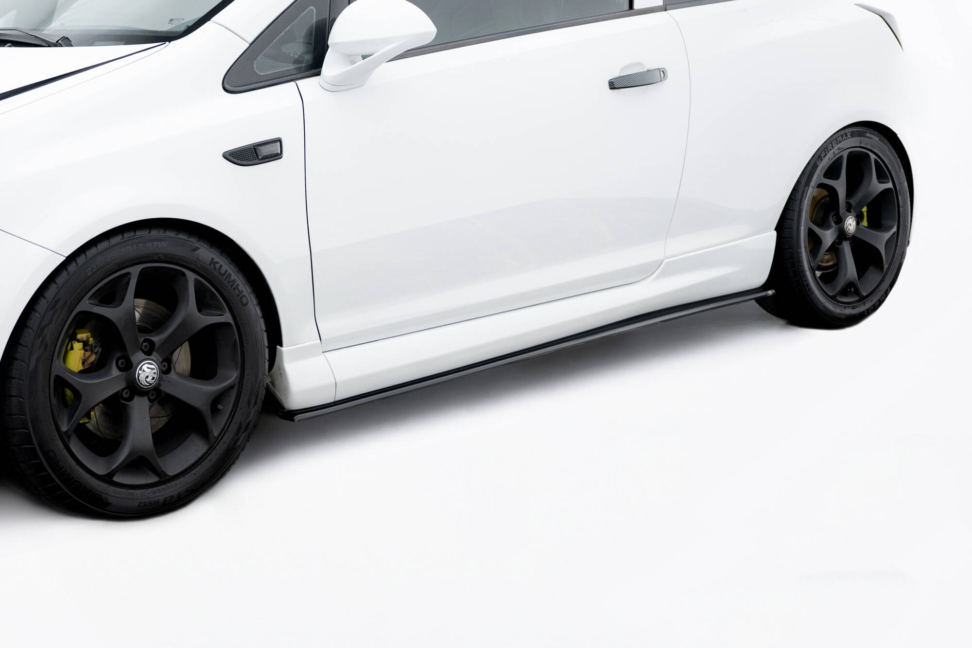 pol_po_Side-Skirts-Diffusers-suitable-for-Opel-Corsa-OPC-VXR-D-245_3jpg - OPSHOLDERS White sports car side profile with black multi-spoke wheels and yellow brake calipers visible through the rims.