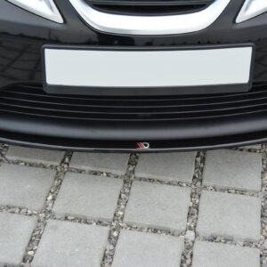 Front view of a black car's bumper with a blank white license plate and a small red-white-black emblem on the lower grille area.