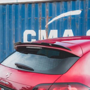 Rear view of a red Citroën hatchback with a blue corrugated metal wall in the background