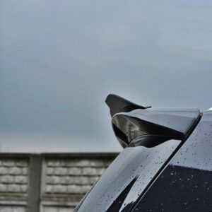 pol_po_Spoiler-Cap-suitable-for-Opel-ZAFIRA-B-OPC-487_6jpg - OPSHOLDERS Close-up of a dark car's glossy rear spoiler with raindrops, set against a cloudy sky and a wooden fence in the background.