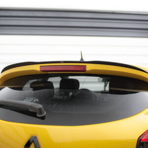 Rear view of a bright yellow hatchback car with a black spoiler and a red high-mounted brake light, parked in front of a white corrugated wall.